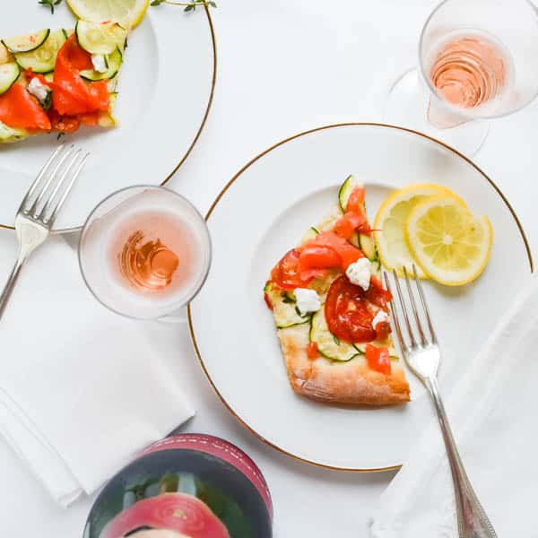Overhead shot of Fresh Smoked Salmon Chèvre Pizza with sparkling wine.
