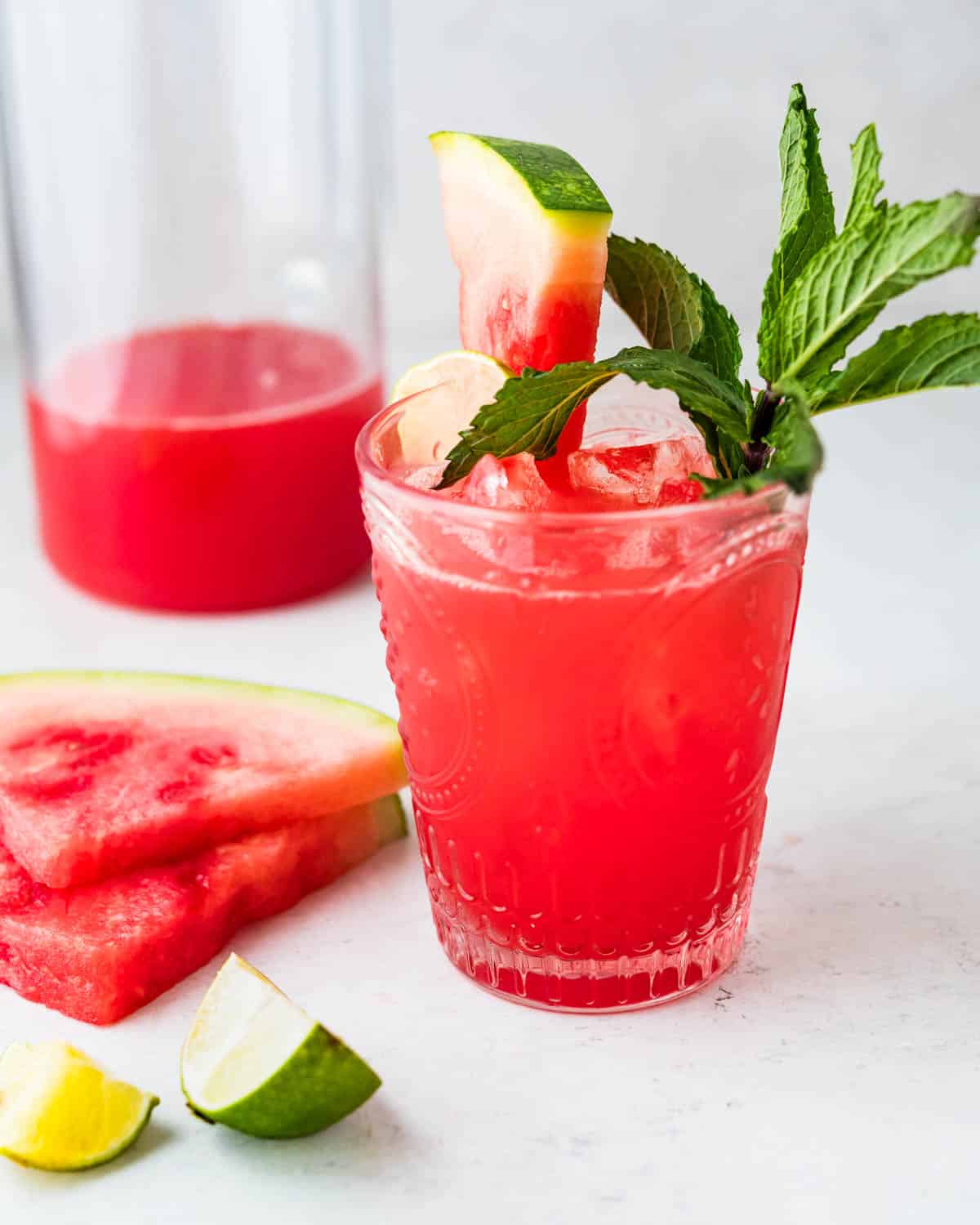 A glass of watermelon water with lime and mint leaves.