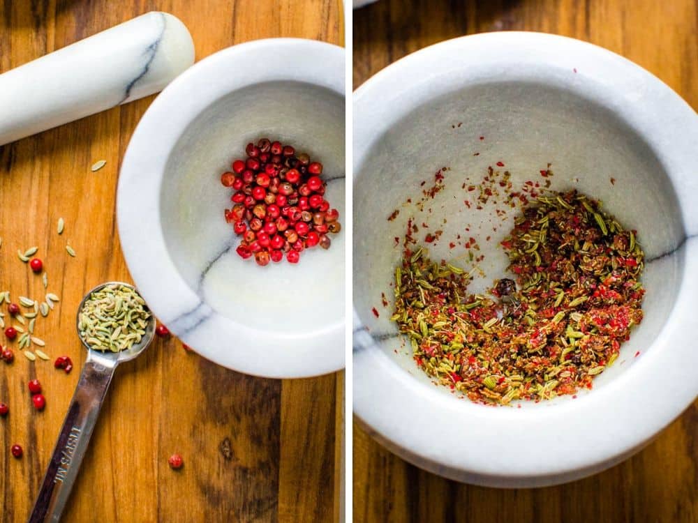 pink peppercorns and fennel seed being crushed in a mortar and pestle for the chicken rub recipe.