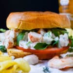 A shrimp sandwich on brioche bun with lettuce and tomato.