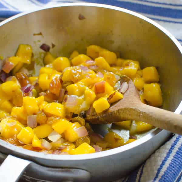 mangoes, onions in a pan with spoon