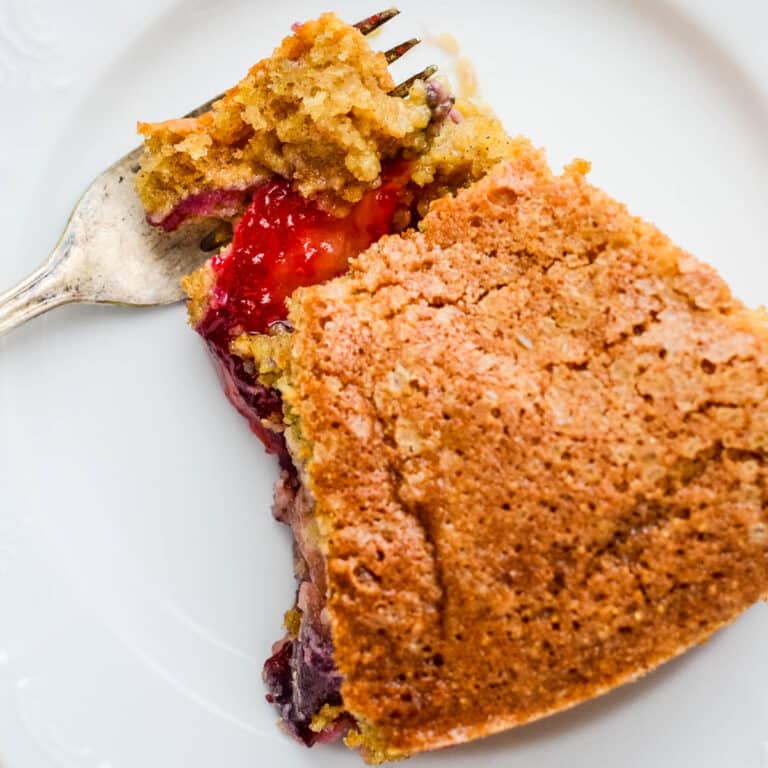 Cornmeal cake with plums on a plate.