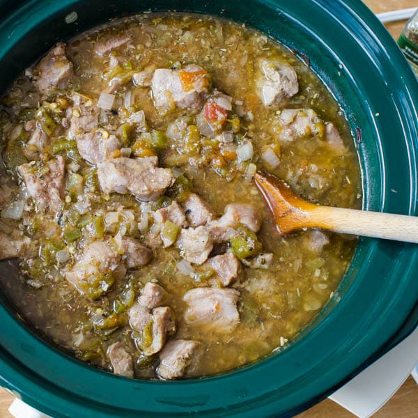 pork and chiles in crock pot with spoon