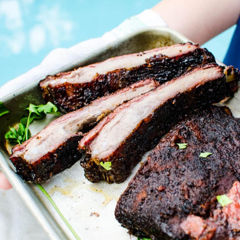 She is serving smoked spareribs on a rimmed baking sheet.