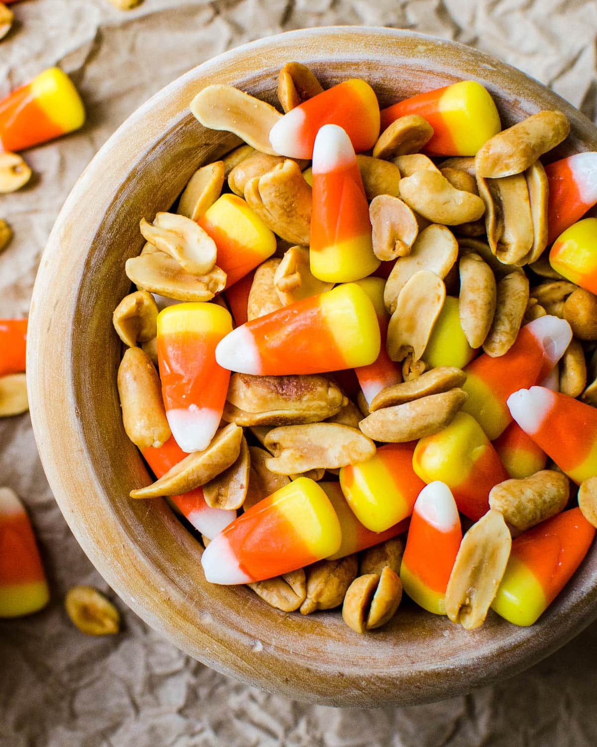 Candy corn and peanut snack mix in a wooden bowl.
