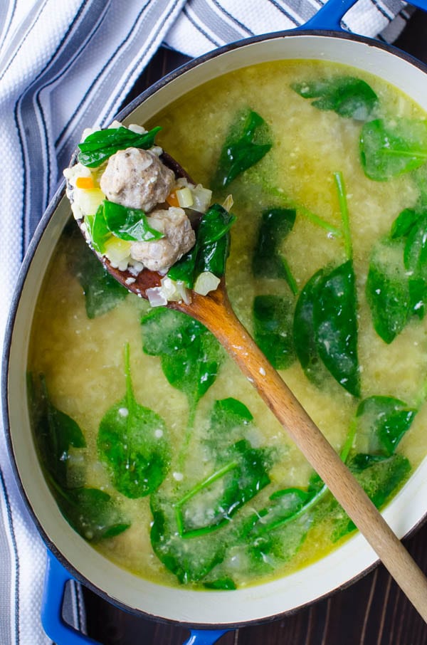 Homemade Italian Wedding Soup in a pot with wooden spoon.