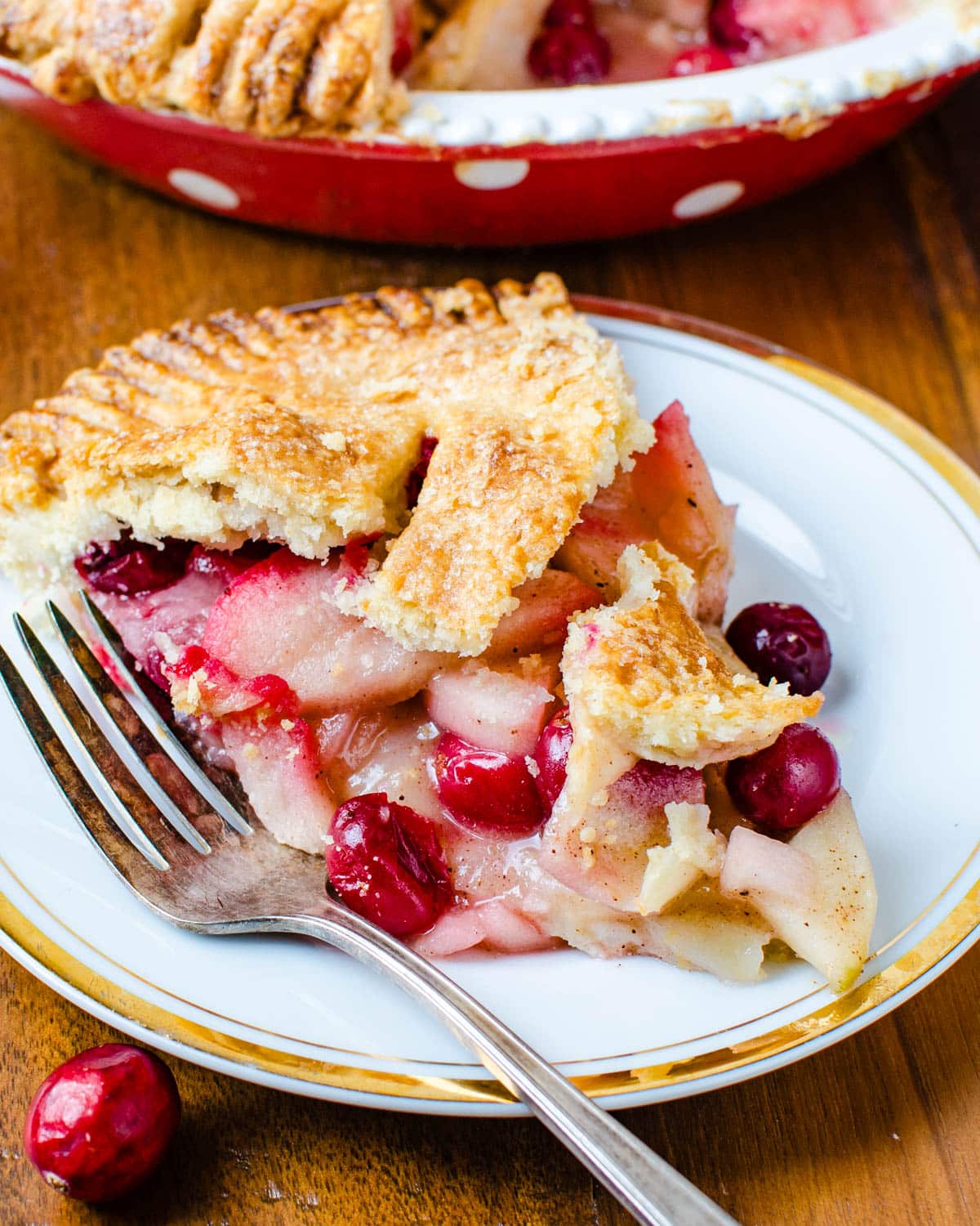 Serving a slice of apple cranberry pie with a fork.