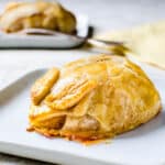 A baked pear covered in pastry on a plate.