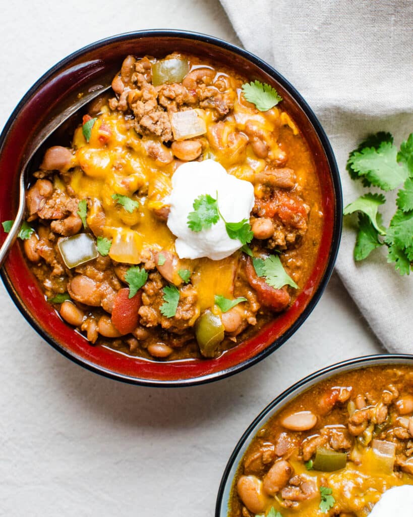 Two bowls of chile con carne with sour cream.