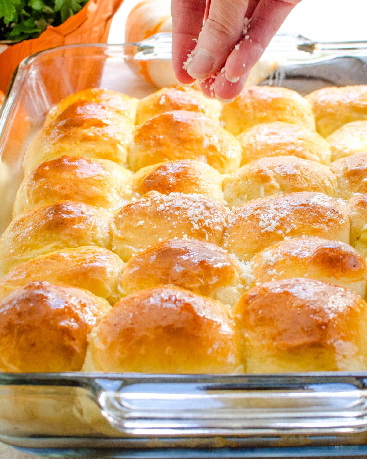 Sprinkling freshly grated parmesan cheese over the yeast rolls.