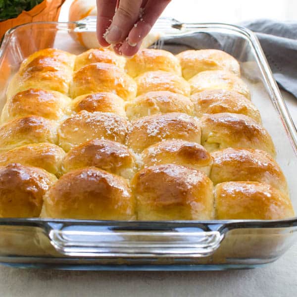Sprinkling Soft Parmesan Dinner Rolls with cheese.