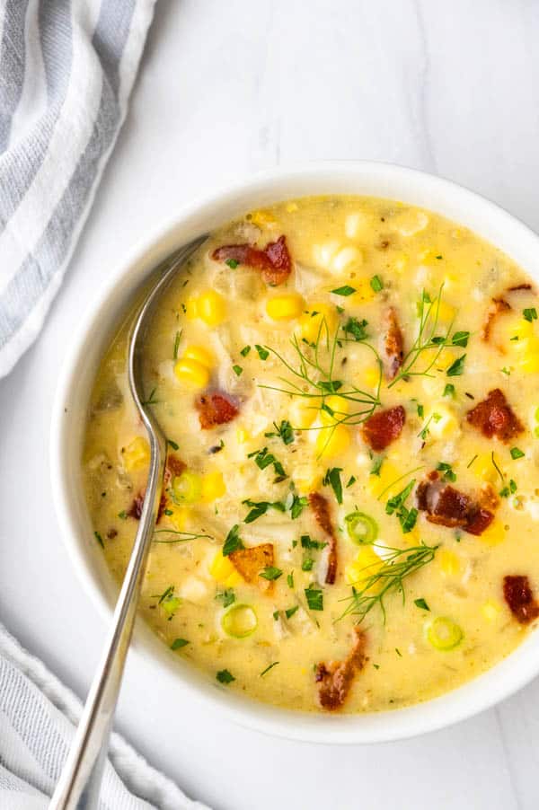 a bowl of easy corn chowder with crumbles of bacon, green onion and fresh herbs.