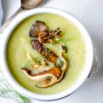 Serving fennel leek soup with wild mushrooms in a white bowl.