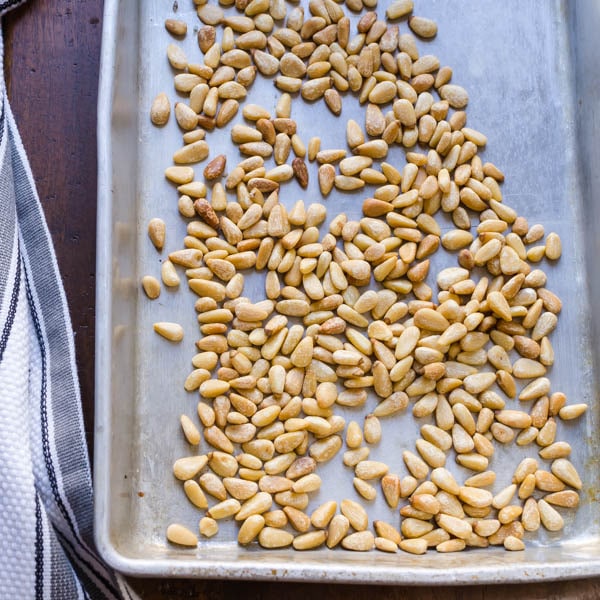 toasted pine nuts on a baking sheet.