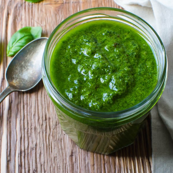 bright green pesto in a jar with a spoon.
