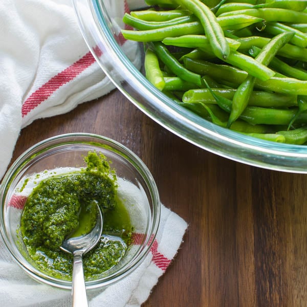 basil pesto next to a bowl of blanched green beans.