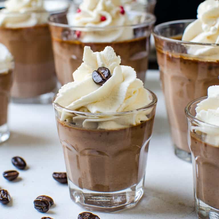 glasses of chocolate pots de creme with kahlua whipped cream and coffee beans.