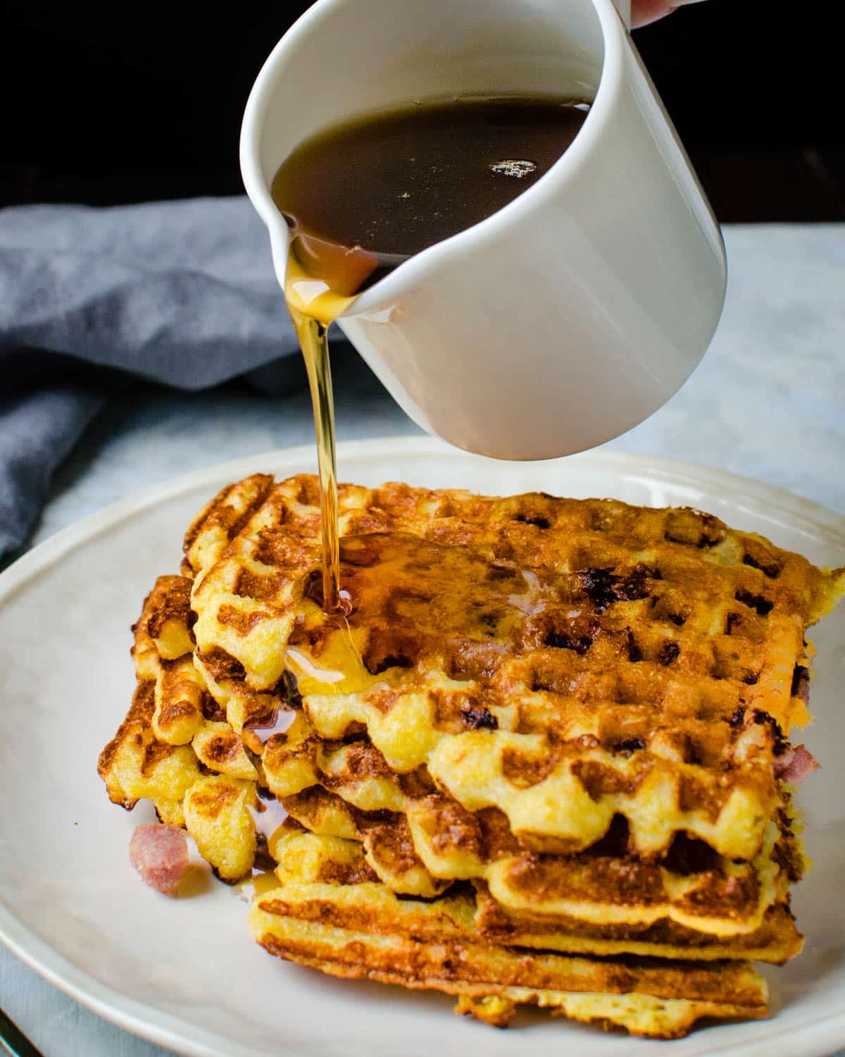 Pouring syrup on a stack of savory waffles.