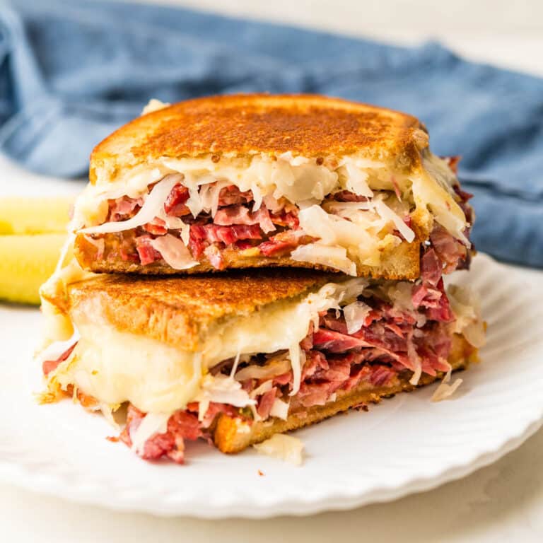 Corned beef Reuben with a side of pickles.