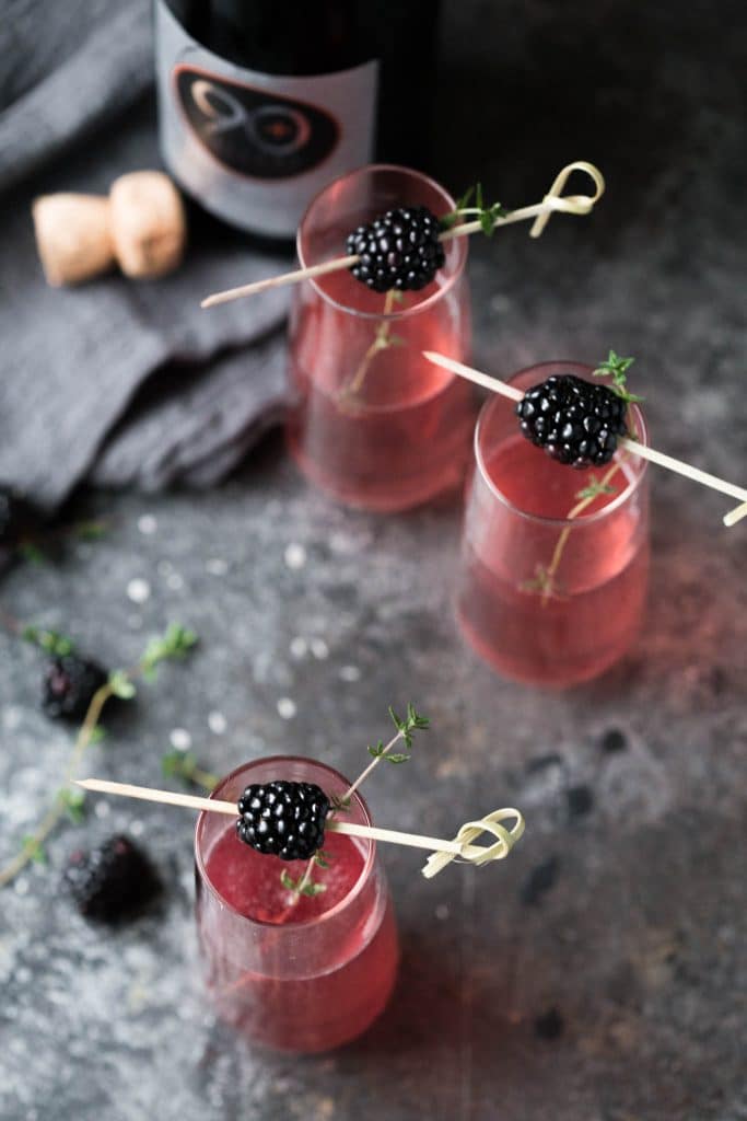 blackberry beelines in small flute glasses with blackberry garnishes.