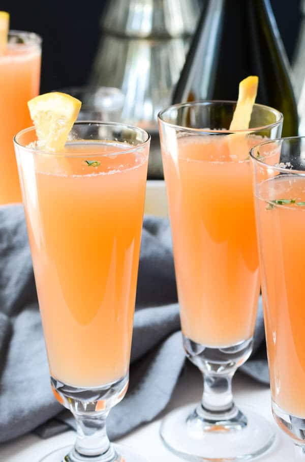 ruby thyme spritzers in champagne flutes with grapefruit garnish.