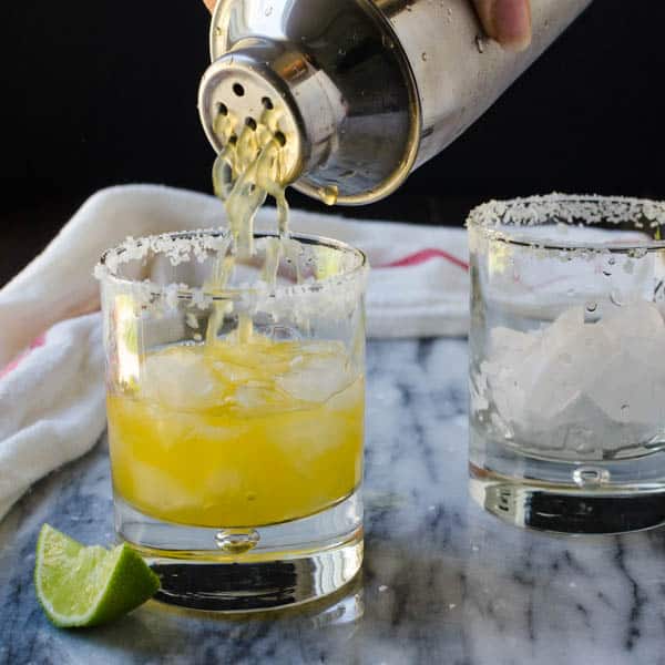 straining the margaritas through a boston shaker sieve into a prepared glass