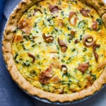 A bacon cheddar and kale quiche in a pie plate.