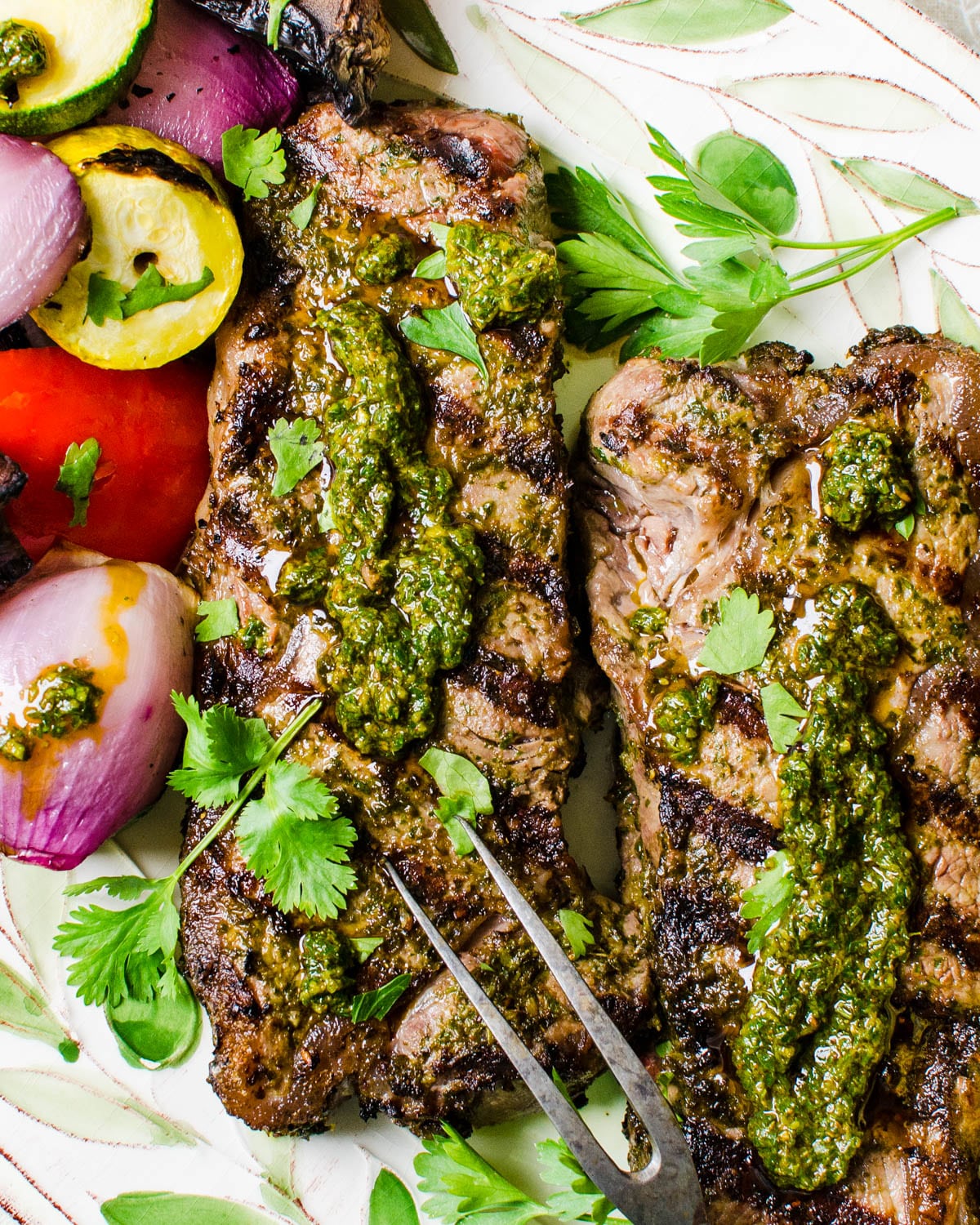 Grilled strip steaks with chermoula sauce and vegetables.