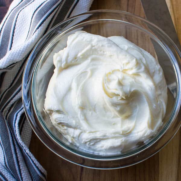 bowl of classic cream cheese frosting in a bowl on a cutting board.