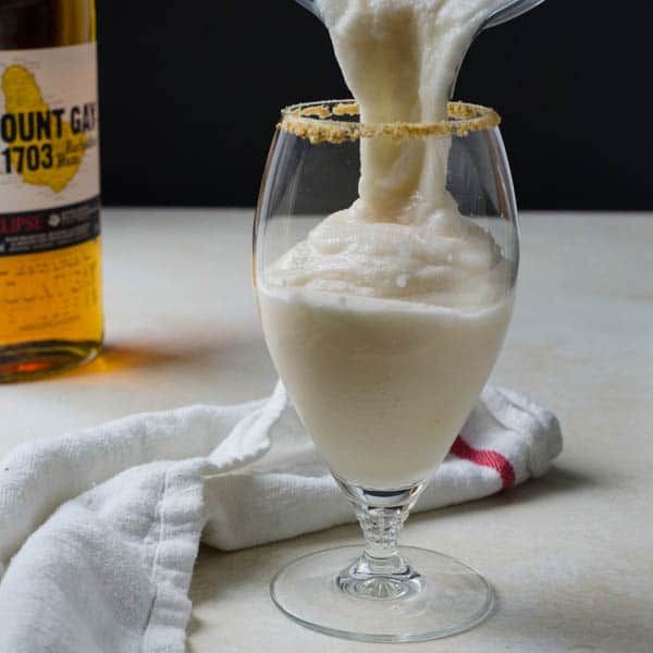 Pouring key lime colada into a prepared glass.