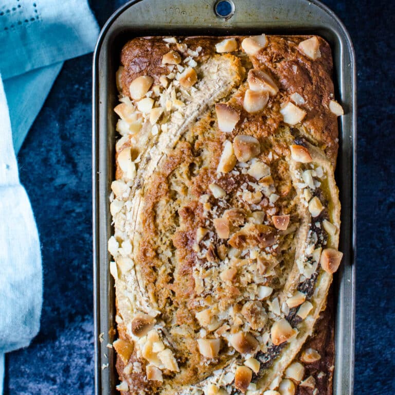 A loaf of coconut macadamia banana bread in a loaf pan.