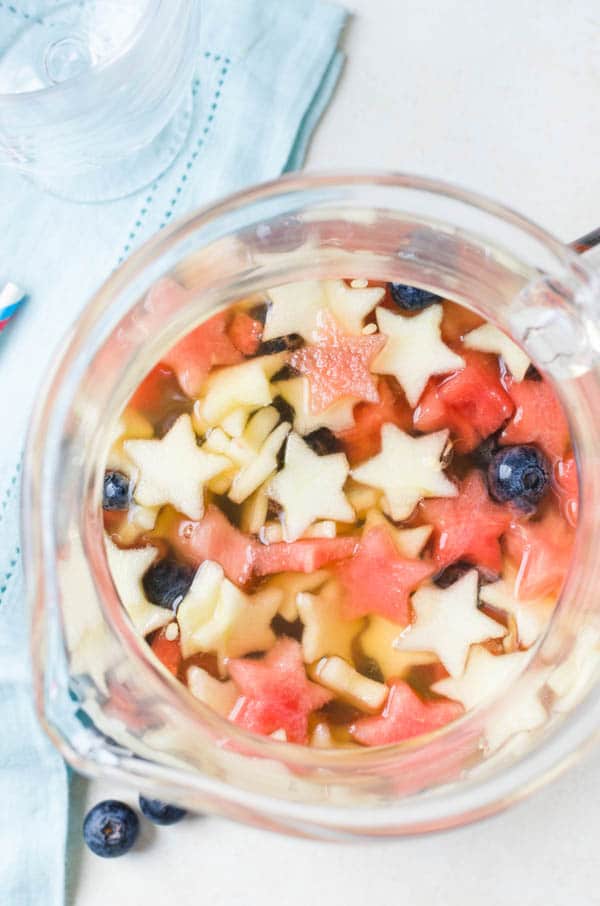 sangria in a pitcher with apples, watermelon and blueberries.