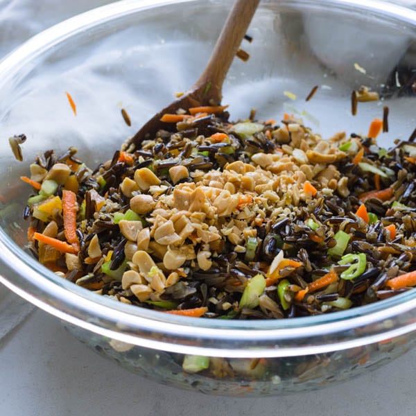 tossing peanuts and dressing with Asian Wild Rice Salad.