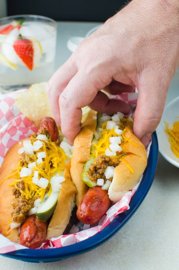 a hand grabbing a chili cheese dilly dog