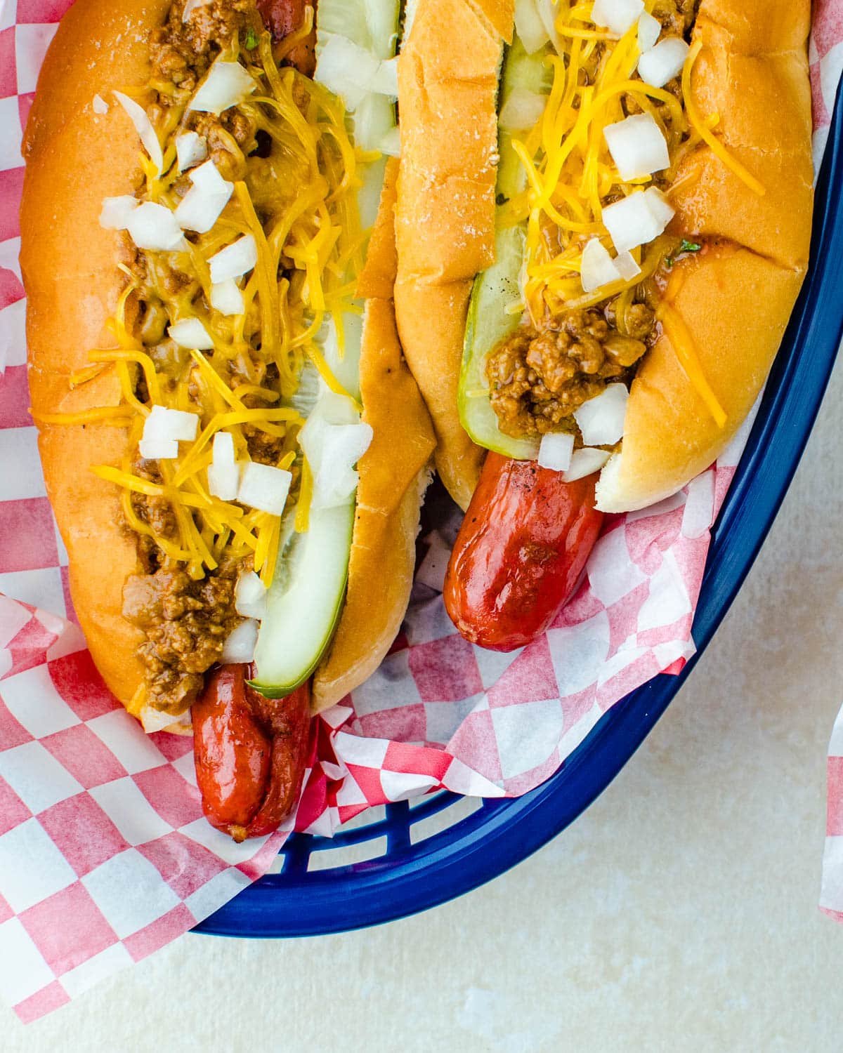 Chili cheese dogs in a basket with all the toppings.