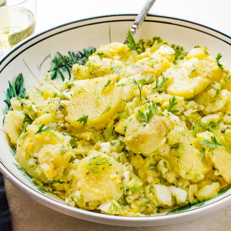 A serving bowl of no mayo potato salad with capers and dill.