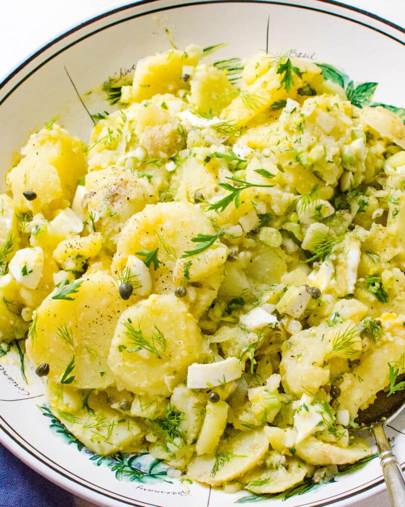 A serving bowl filled with french potato salad.