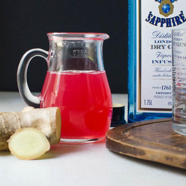 rhubarb ginger simple syrup in a pitcher with a bottle of gin.