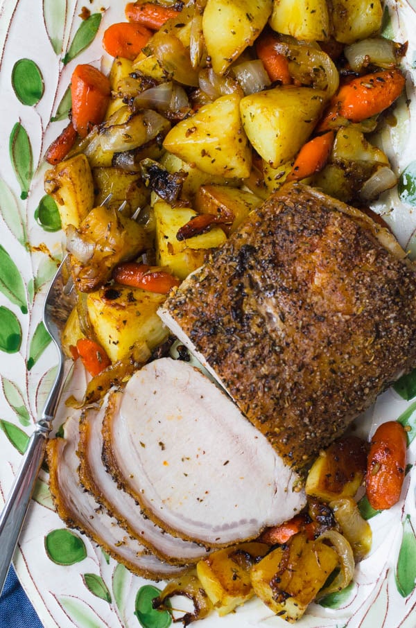 Herb Crusted Pork Loin on a platter with vegetables.