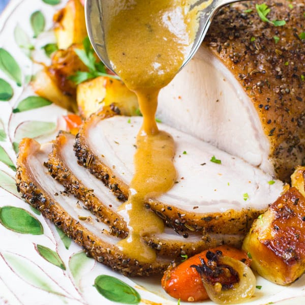 Herb Crusted Pork Loin with Pan Gravy being spooned over.
