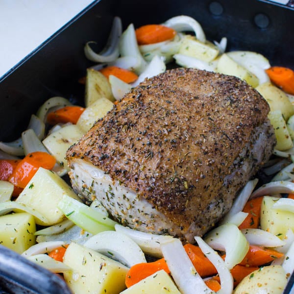 adding vegetables to herb crusted pork loin