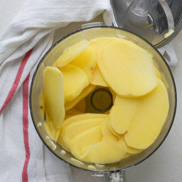 slicing potatoes in a food processor for a fall side dish of Simple Scalloped Potatoes
