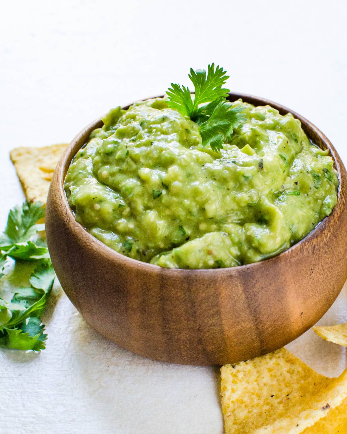 A wooden bowl filled with creamy avocado salsa.