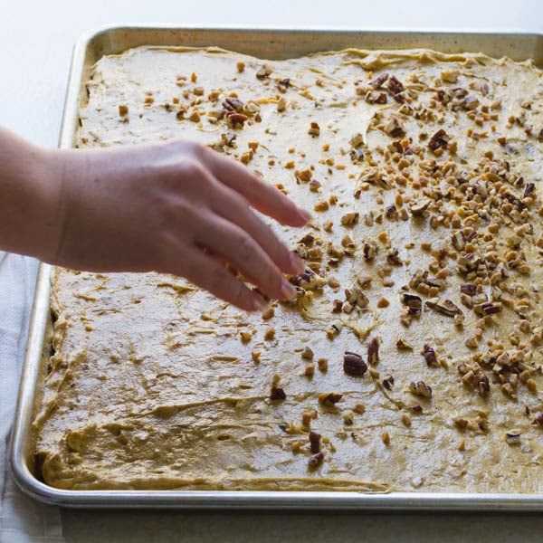 topping pumpkin blondies with brickle and nuts.