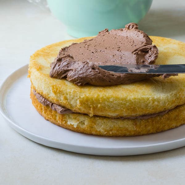 spreading milk chocolate frosting on the moist yellow cake.