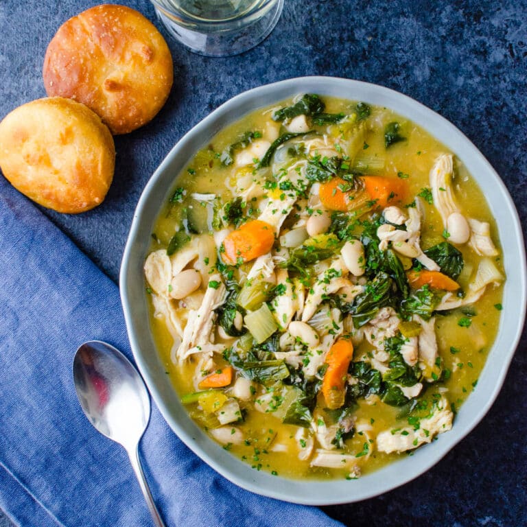 A bowl of healthy chicken stew with muffins.
