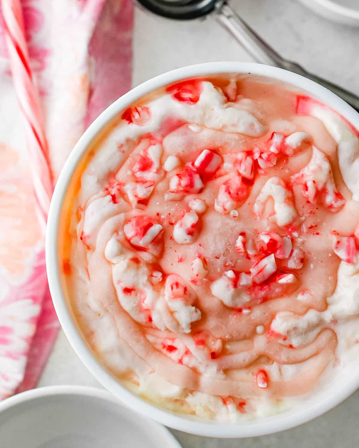 A quart of peppermint ice cream with candy canes on top.