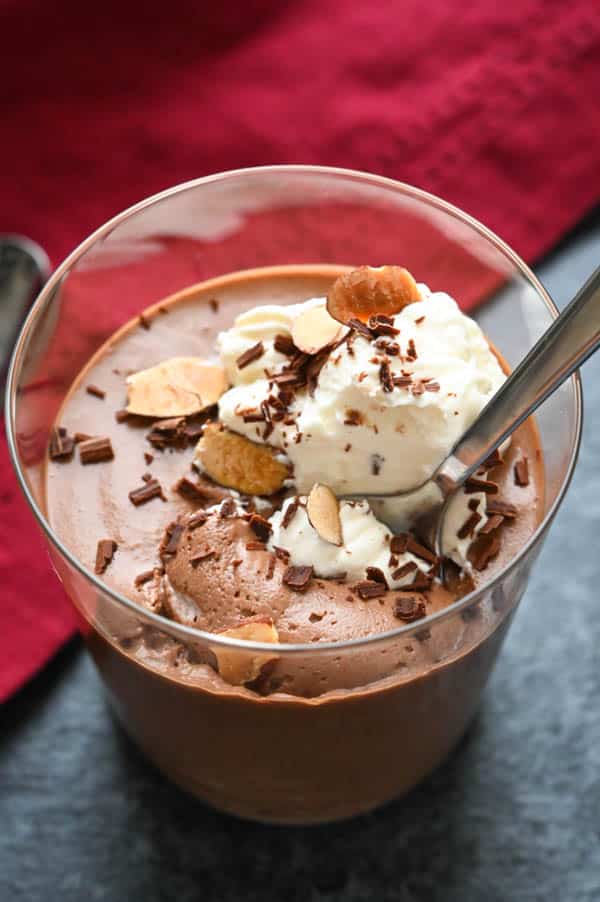 Serving simple chocolate mousse with whipped cream, chocolate shavings and toasted almonds.