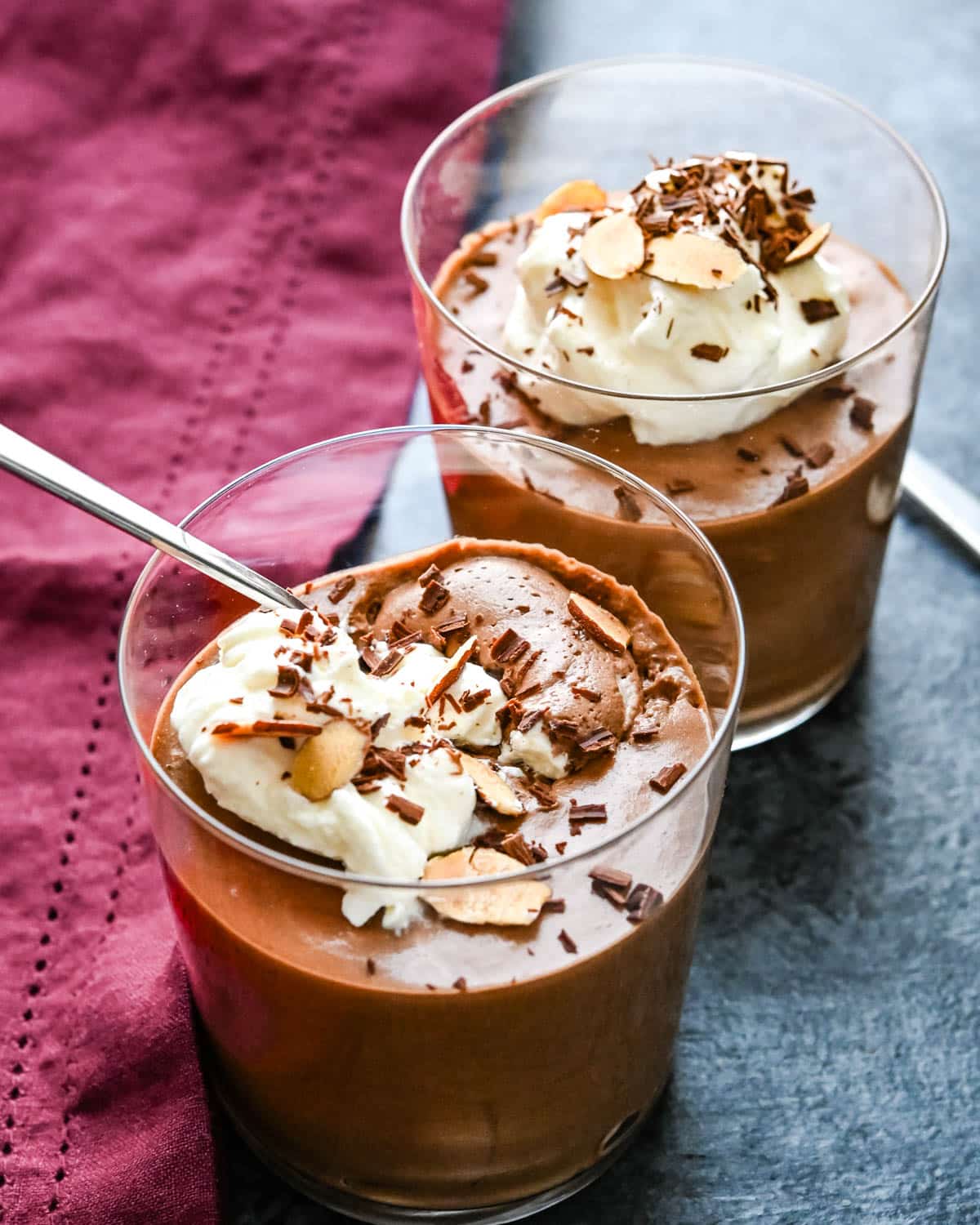 Two chocolate mousses with whipped cream and chocolate shavings.