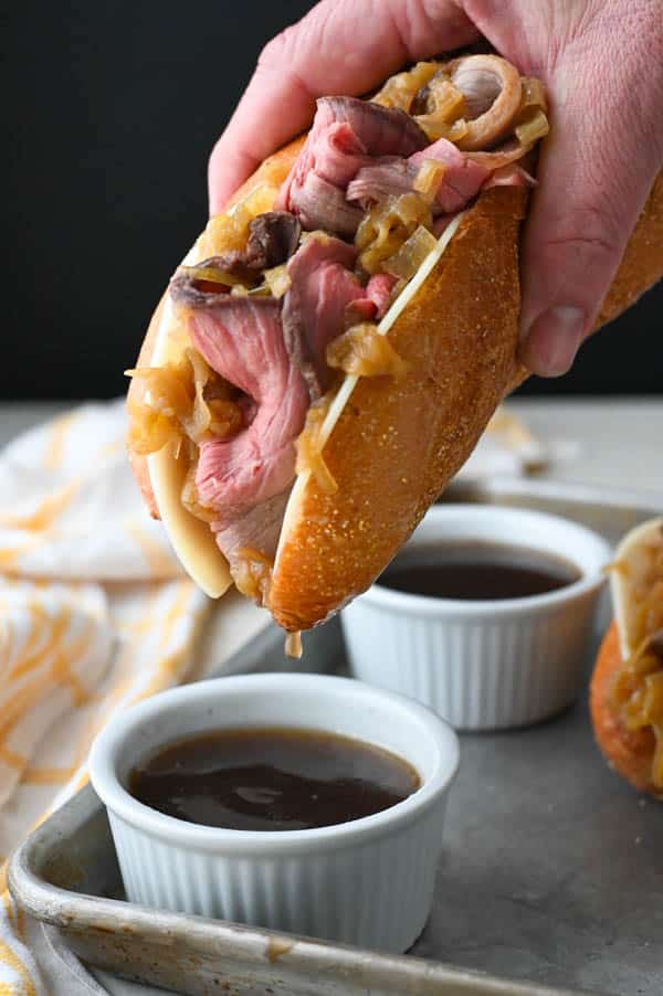 Dipping the sliced roast beef sandwich into the jus.